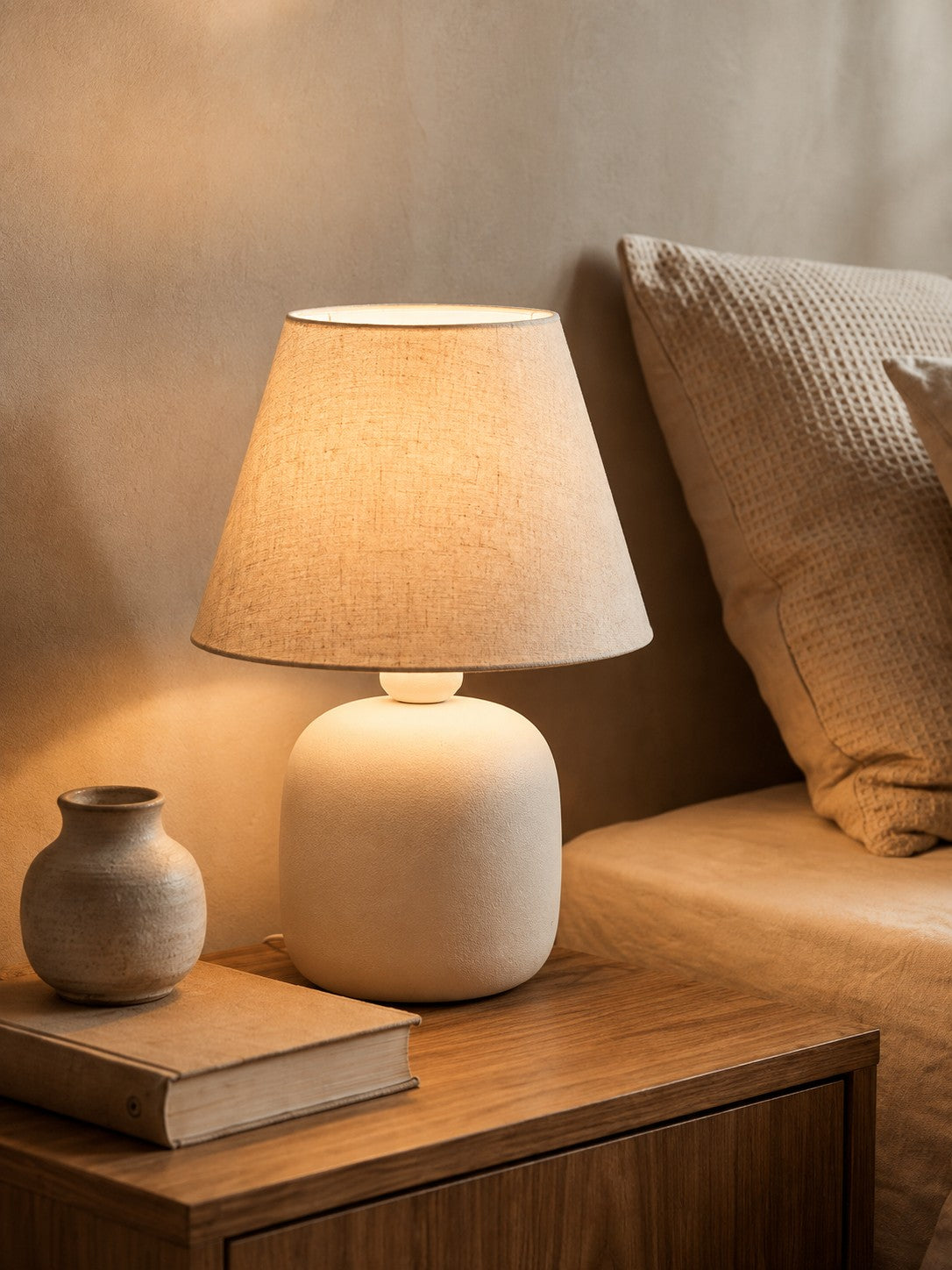 Abajur de cerâmica off white espalhando luz quente no quarto - Vittara Decor
