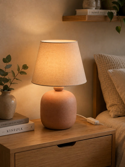 Abajur de cerâmica rosa queimado aceso no criado-mudo do quarto - Vittara Decor