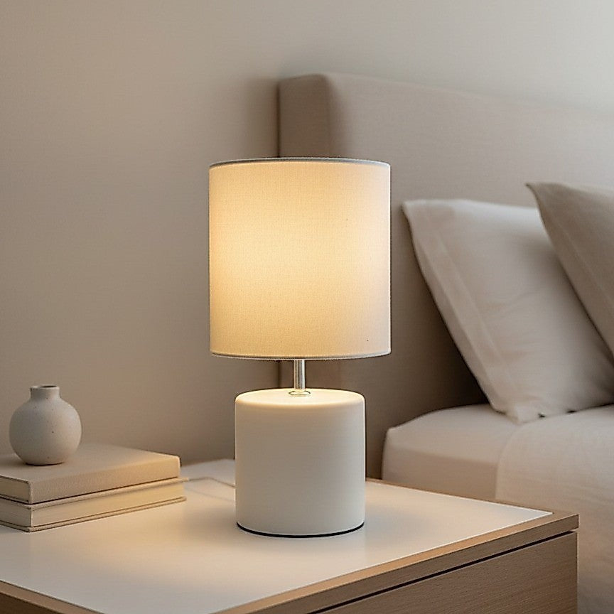 Abajur de cerâmica cilindro off white aceso na cabeceira da cama - Vittara Decor