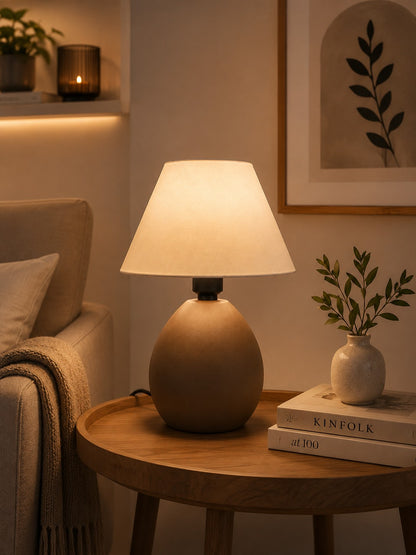 Abajur de cerâmica elipse capuccino no cantinho de leitura ao lado do sofá - Vittara Decor