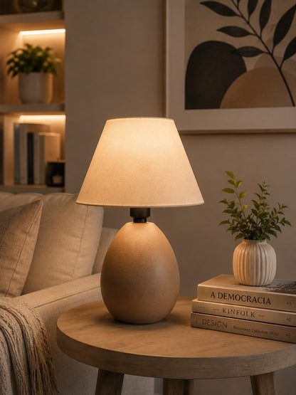 Abajur de cerâmica elipse capuccino aceso em mesa lateral da sala - Vittara Decor