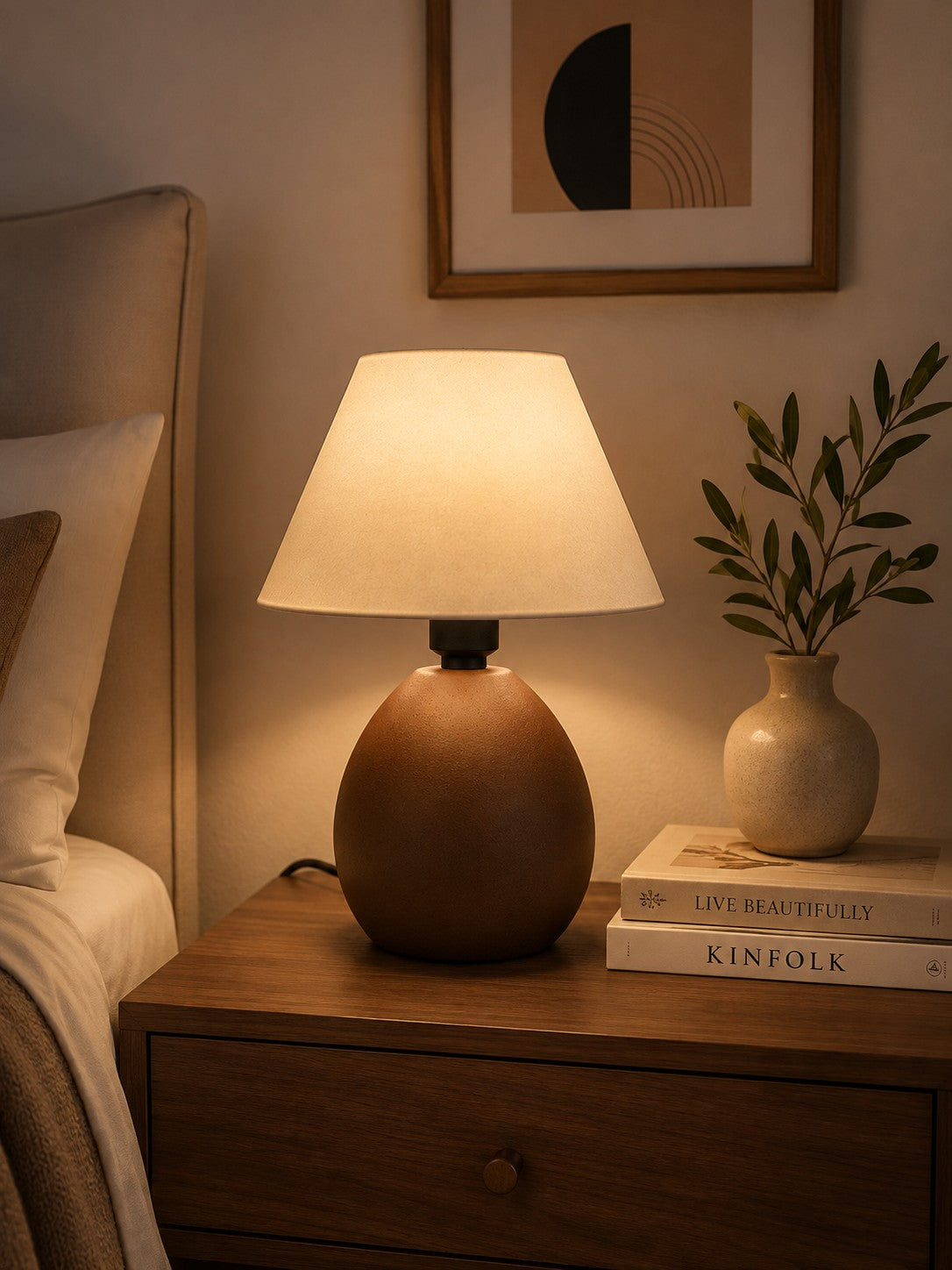 Abajur de cerâmica elipse marrom aceso na cabeceira da cama - Vittara Decor