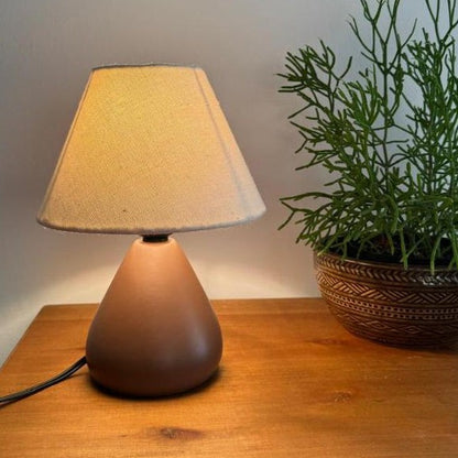 Abajur de cerâmica gota marrom escuro ao lado de vaso de planta - Vittara Decor