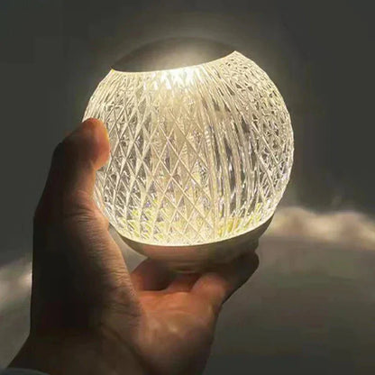 Abajur de cristal esfera segurado na mao, com luz quente brilhando pelas facetas - Vittara Decor