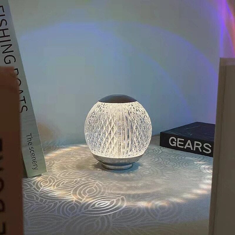 Abajur de cristal aceso na mesa de cabeceira com livros ao lado - Vittara Decor