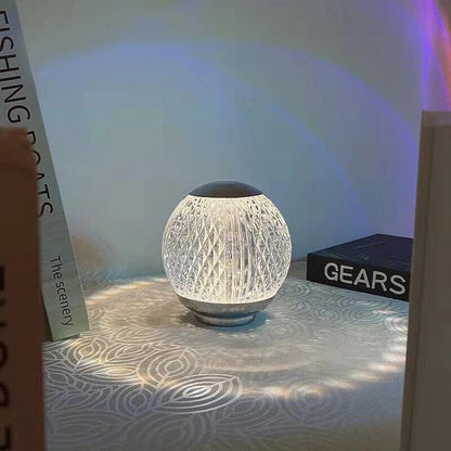 Abajur de cristal aceso na mesa de cabeceira com livros ao lado - Vittara Decor