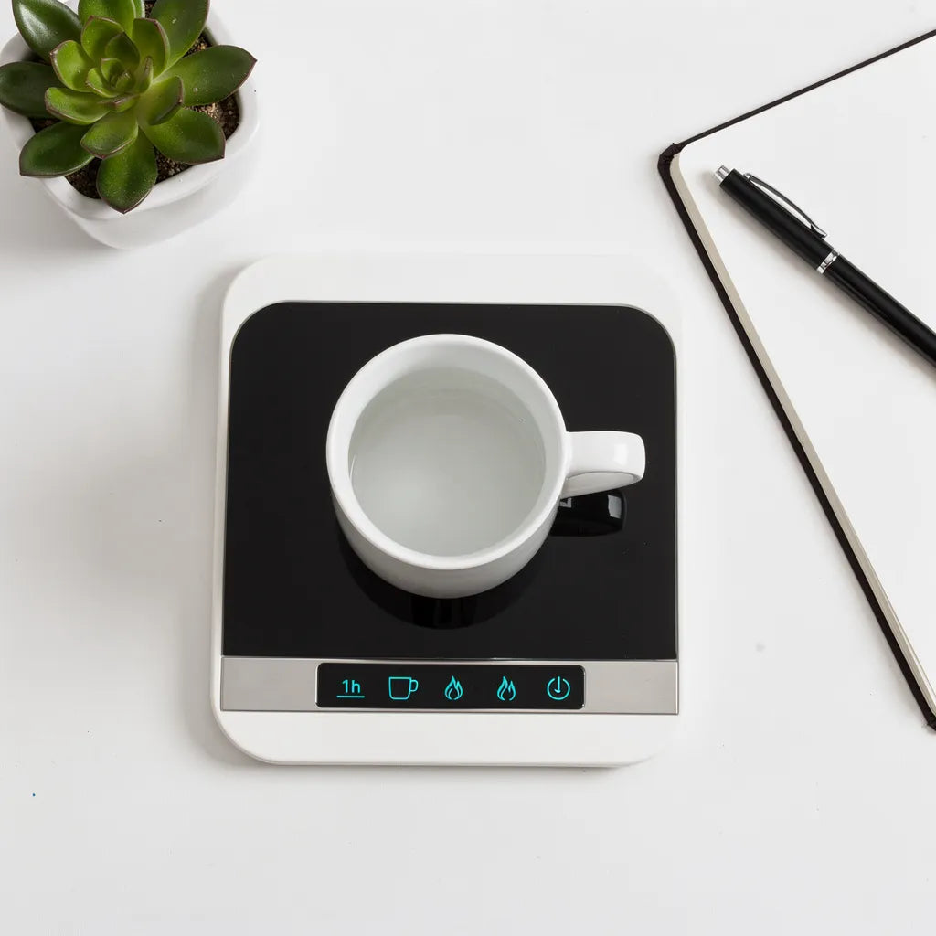 Flat lay aereo aquecedor de canecas USB em mesa branca com caneca notebook e planta — Vittara Decor