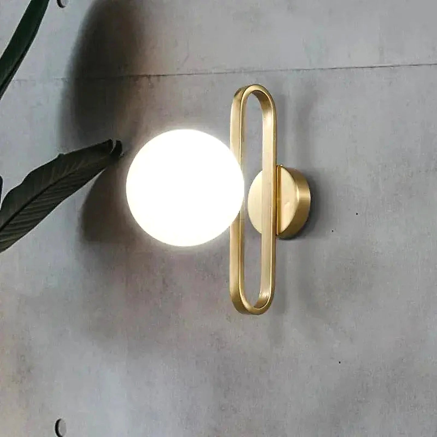 Arandela de Parede Dourada LED G9 em parede de concreto com folhagem decorativa