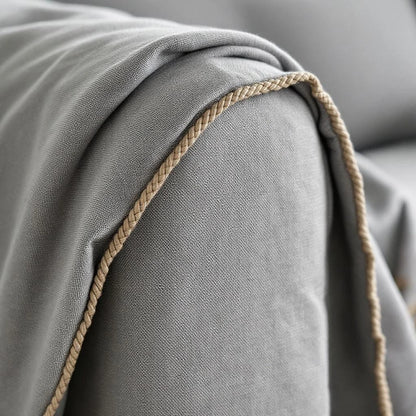 Detalhe do caimento e borda trançada bege da capa de sofá cinza — Vittara Decor