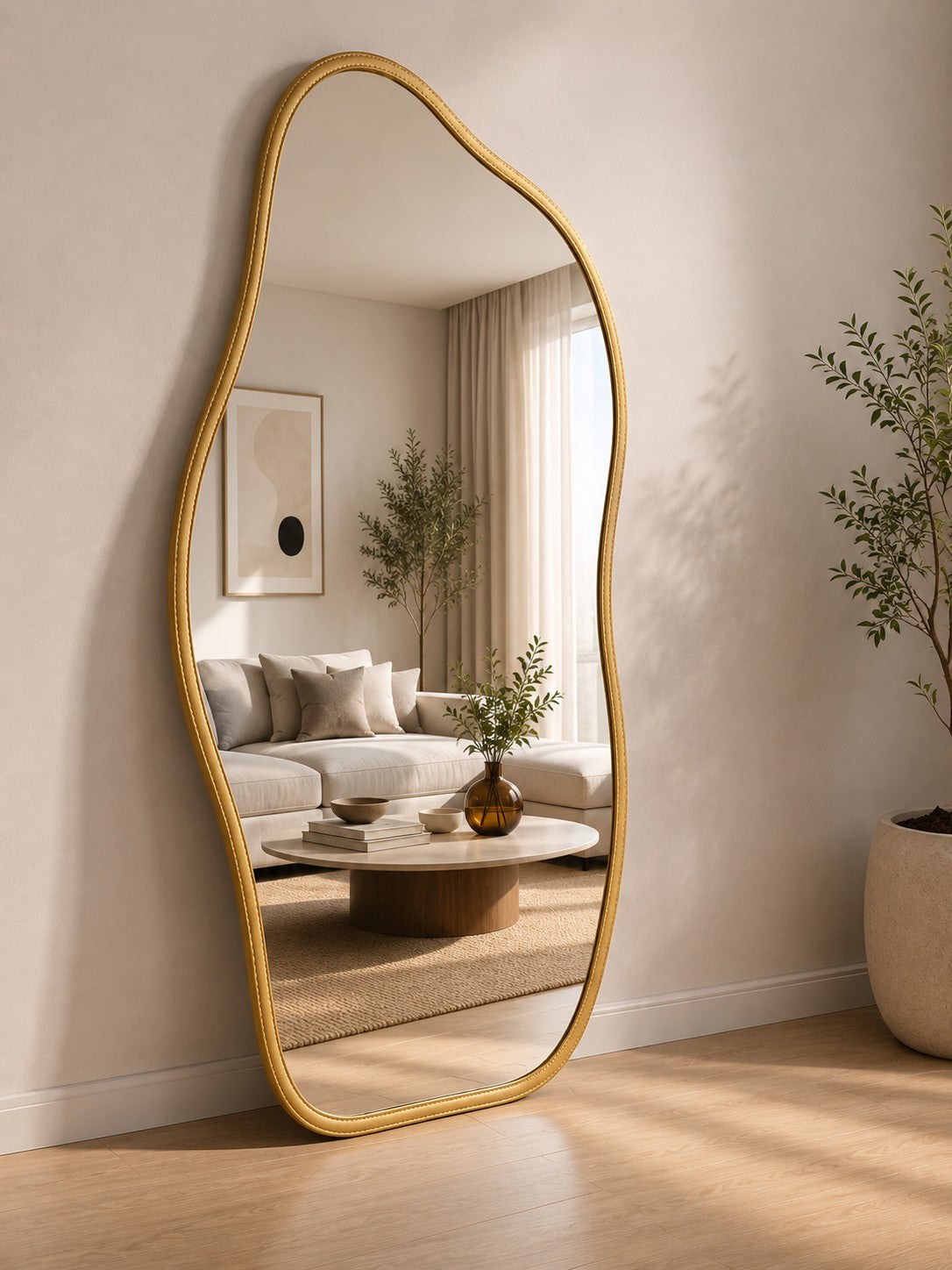 Espelho orgânico de corpo inteiro dourado refletindo o sofá da sala - Vittara Decor