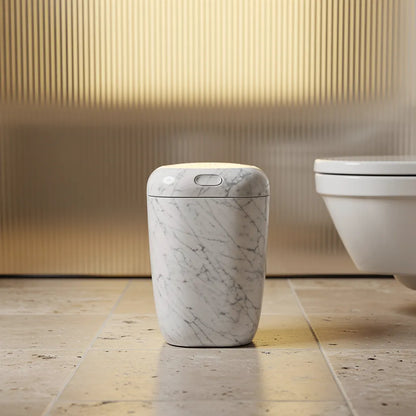 Lixeira multiuso com tampa design moderno mármore branco ao lado do vaso em banheiro com painel dourado - Vittara Decor