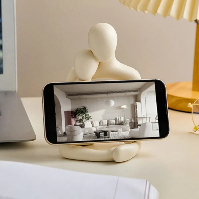 Luminária de casal abraçado usada como suporte de celular na mesa - Vittara Decor