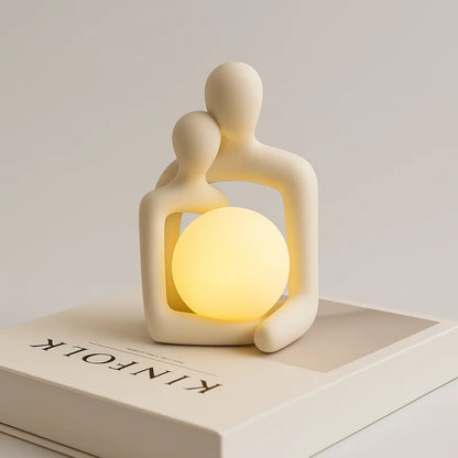 Luminária de casal reclinado com globo LED aceso sobre livro - Vittara Decor