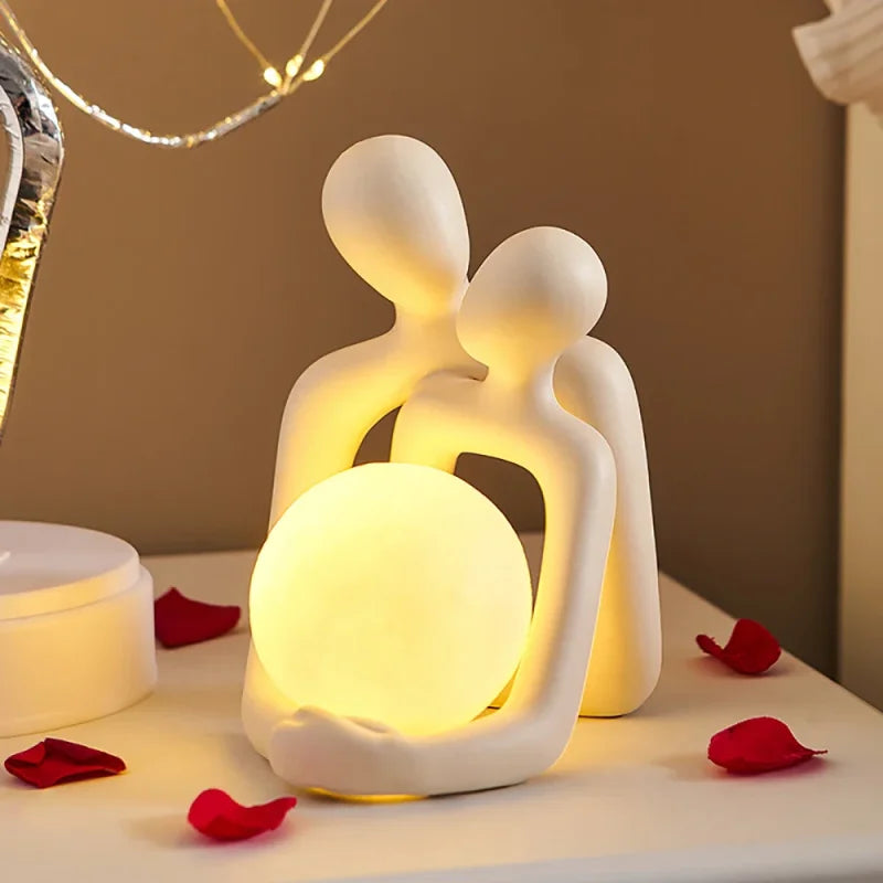 Luminária de casal abraçado em pé com esfera LED acesa na cabeceira - Vittara Decor