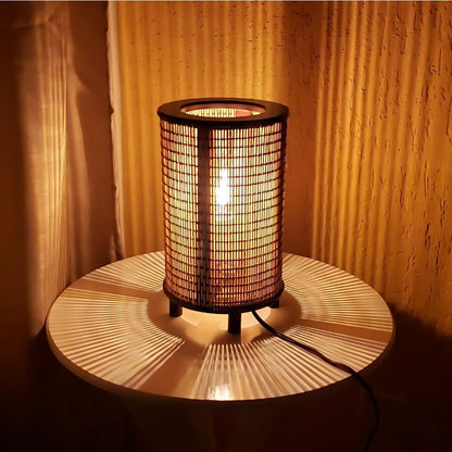 Luminária de mesa de fibra natural acesa sobre mesa de madeira - Vittara Decor