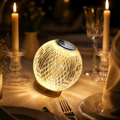 Luminária esfera facetada acesa na mesa de jantar entre velas