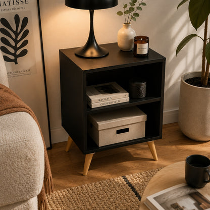 Mesa de cabeceira retrô preta com pés palito e dois nichos abertos na sala - Vittara Decor