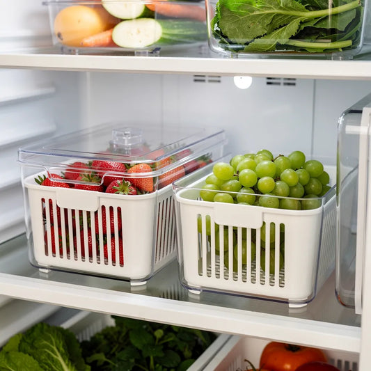 Organizador de geladeira transparente com cesto branco dentro da geladeira aberta com morangos e uvas - Vittara Decor
