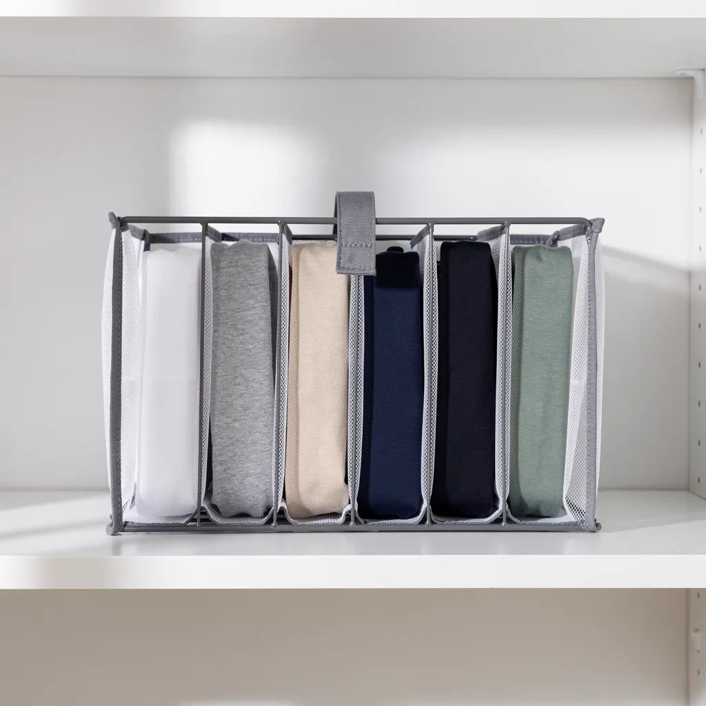 Organizador de roupas com 7 camisetas dobradas verticalmente método KonMari em cores branco cinza bege azul marinho e verde sálvia na prateleira - Vittara Decor
