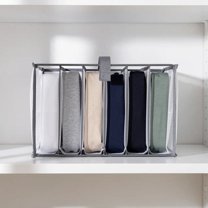 Organizador de roupas com 7 camisetas dobradas verticalmente método KonMari em cores branco cinza bege azul marinho e verde sálvia na prateleira - Vittara Decor