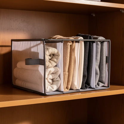 Organizador separador de roupas com suéteres e moletons dobrados verticalmente em tons neutros dentro de closet de madeira aquecido - Vittara Decor