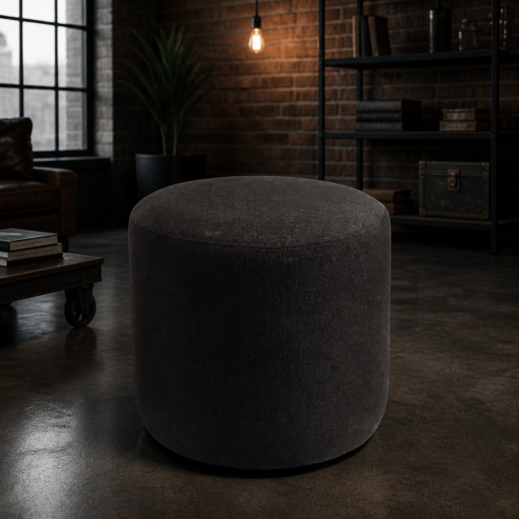 Puff Redondo Suede preto em ambiente industrial com tijolo exposto - Vittara Decor