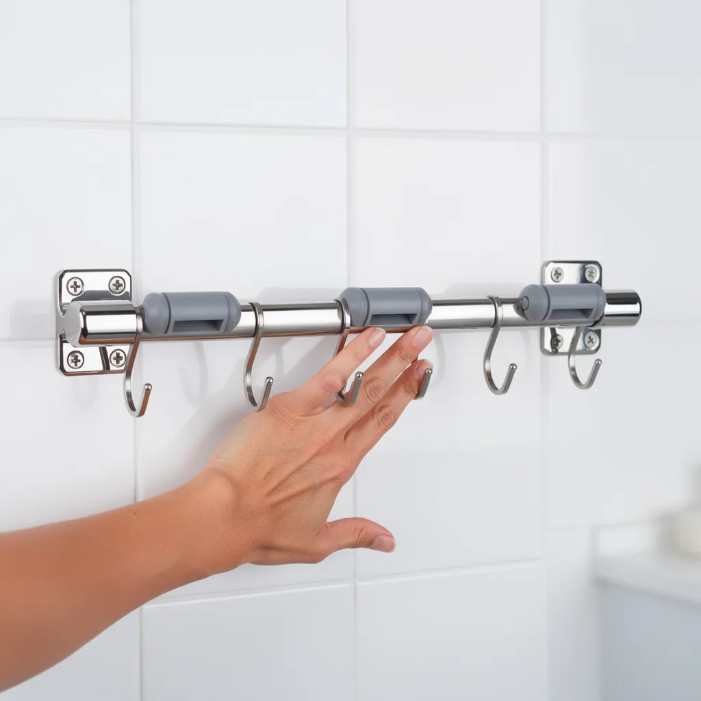 Instalação do suporte para vassouras inox mão pressionando trilho contra parede de azulejo mostrando fixação - Vittara Decor