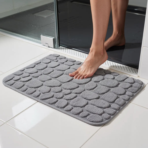 Tapete antiderrapante absorvente cinza em algodão com padrão seixos na saída do box com pé pisando na - Vittara Decor