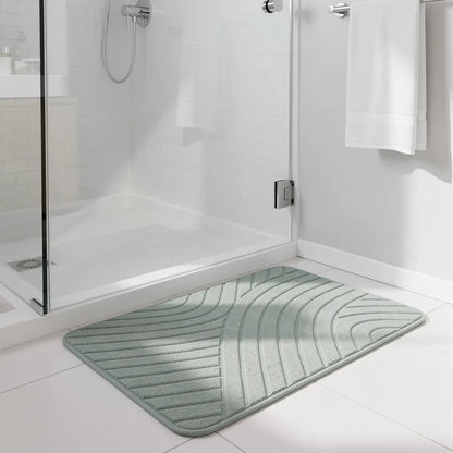 Tapete de diatomita cinza claro posicionado na saída do box de vidro em banheiro moderno com azulejo branco - Vittara Decor