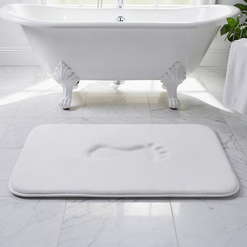 Tapete antiderrapante veludo branco posicionado em frente à banheira freestanding em banheiro claro com luz natural - Vittara Decor