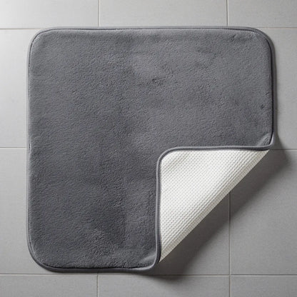 Tapete veludo cinza parcialmente levantado mostrando a base antiderrapante off-white que evita deslizamento no piso - Vittara Decor